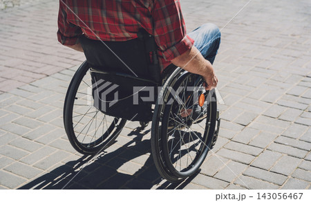 Young man with a physical disability in a wheelchair walk at the street Young man with a physical disability in a wheelchair walk at the street 143056467