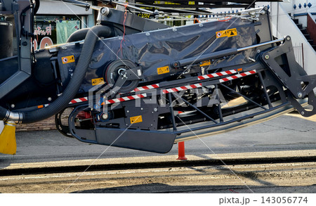 Road paving machine laying fresh asphalt on urban street during clear daylight 143056774