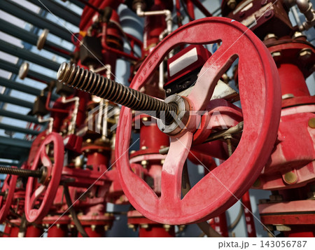 Red industrial valve wheel on steel piping network with threaded stem Red industrial valve wheel on steel piping network with threaded stem 143056787