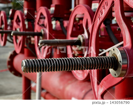 Red industrial valve wheel on steel piping network with threaded stem Red industrial valve wheel on steel piping network with threaded stem 143056790