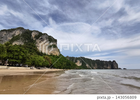 Tropical beach with calm ocean and soft blue sky above tranquil shoreline Tropical beach with calm ocean and soft blue sky above tranquil shoreline 143056809