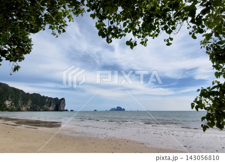 Tropical beach with calm ocean and soft blue sky above tranquil shoreline 143056810