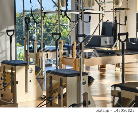 Spacious pilates reformer studio with rows of wooden machines Spacious pilates reformer studio with rows of wooden machines 143056825