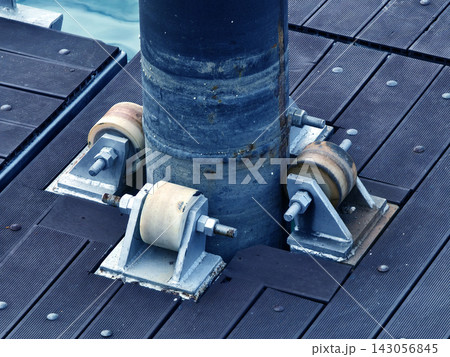 Rusty metal pipe support with three roller wheels on weathered wooden deck in sunlight Rusty metal pipe support with three roller wheels on weathered wooden deck in sunlight 143056845
