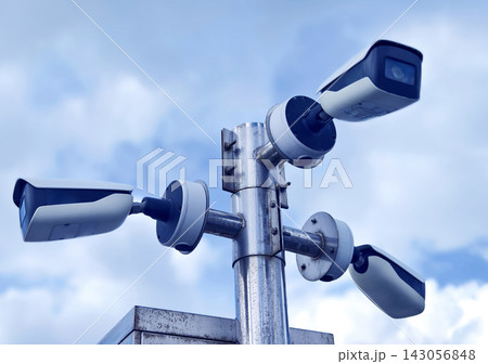 Cluster of outdoor security cameras mounted on metal pole watching property 143056848