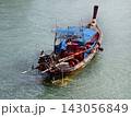 Wooden longtail fishing boat with blue canopy and exposed outboard motor 143056849