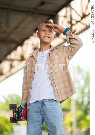 Fair-haired boy of school age with a skateboard looking confident Fair-haired boy of school age with a skateboard looking confident 143057796
