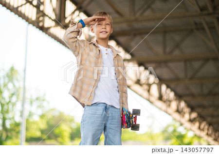 Fair-haired boy of school age with a skateboard looking confident Fair-haired boy of school age with a skateboard looking confident 143057797