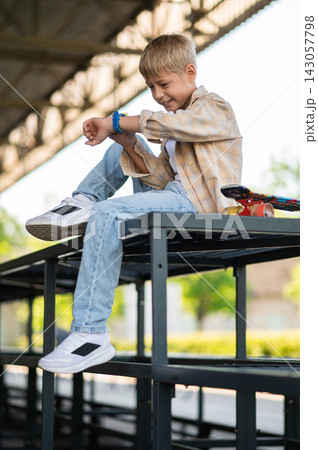 Young skateboarder resting after a skateboard ride and looking relaxed Young skateboarder resting after a skateboard ride and looking relaxed 143057798