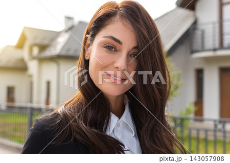 Headshot of a cute long-haired young woman on a house background Headshot of a cute long-haired young woman on a house background 143057908