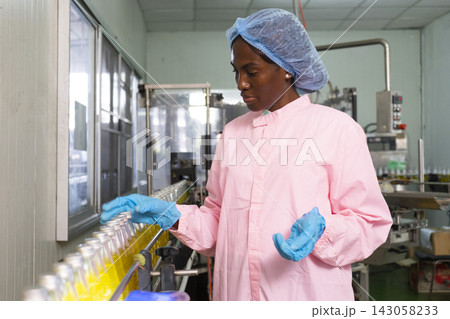 Black female QC worker checking production line safety and hygienic standard in food and drink factory. Black female QC worker checking production line safety and hygienic standard in food and drink factory. 143058233