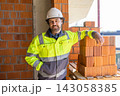 Construction worker standing beside brick stack indoors 143058385