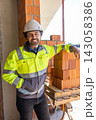 Construction worker leaning against stack of bricks 143058386