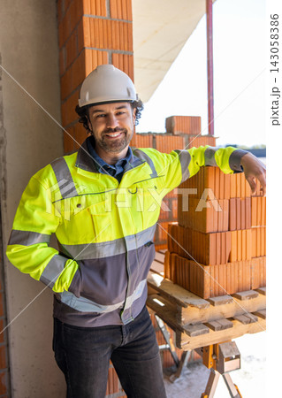 Construction worker leaning against stack of bricks Construction worker leaning against stack of bricks 143058386