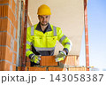 Construction worker holding trowel and brick outdoors 143058387