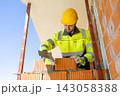 Construction worker holding trowel near brick wall 143058388