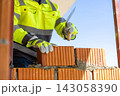 Construction worker laying brick with trowel on site 143058390