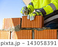 Construction worker laying red brick using trowel and mortar 143058391