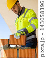 Professional mason wearing safety gloves placing orange ceramic block 143058396