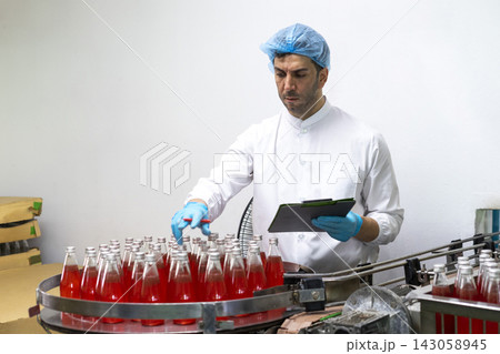 Male workers in factory checking products. Workers inspecting production line at drinks production factory.  143058945