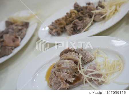 The dish of sliced cooked meat, garnished with thin slices of ginger The dish of sliced cooked meat, garnished with thin slices of ginger 143059136