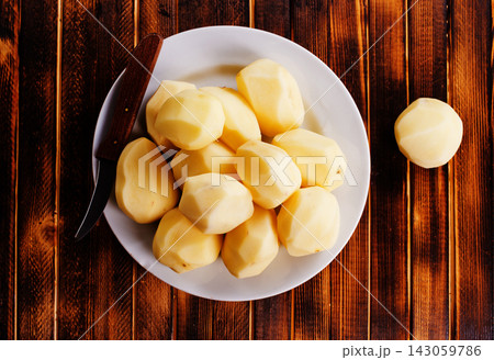 Plate with raw potatoes on wooden background 143059786