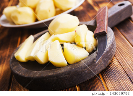 Plate with raw potatoes on wooden background 143059792