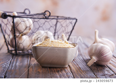 Ginger powder in a bowl, surrounded by garlic cloves 143059873