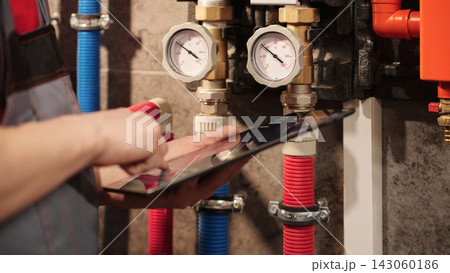 Plumber Or HVAC Technician Entering Heating System Data On Tablet Beside Gauges, Closeup. Digital Maintenance Records And Paperless Field Service Concept. Plumber Or HVAC Technician Entering Heating System Data On Tablet Beside Gauges, Closeup. Digital Maintenance Records And Paperless Field Service Concept. 143060186