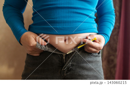 Woman receiving weight loss injections and fat dissolving injections into belly fat at home. Close up of stomach subcutaneous injection, lipolytic, fertility hormone, or insulin therapy. Woman receiving weight loss injections and fat dissolving injections into belly fat at home. Close up of stomach subcutaneous injection, lipolytic, fertility hormone, or insulin therapy. 143060215