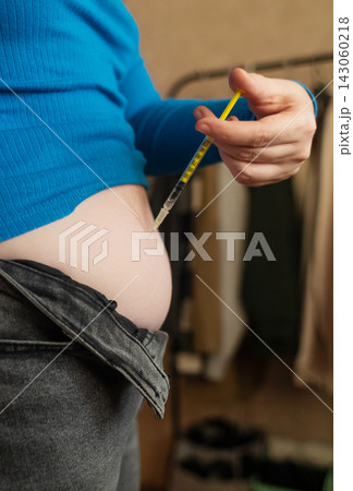 Woman receiving weight loss injections and fat dissolving injections into belly fat at home. Close up of stomach subcutaneous injection, lipolytic, fertility hormone, or insulin therapy. 143060218