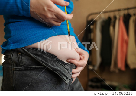 Woman receiving weight loss injections and fat dissolving injections into belly fat at home. Close up of stomach subcutaneous injection, lipolytic, fertility hormone, or insulin therapy. Woman receiving weight loss injections and fat dissolving injections into belly fat at home. Close up of stomach subcutaneous injection, lipolytic, fertility hormone, or insulin therapy. 143060219