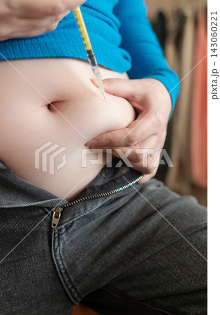 Woman receiving weight loss injections and fat dissolving injections into belly fat at home. Close up of stomach subcutaneous injection, lipolytic, fertility hormone, or insulin therapy. 143060221
