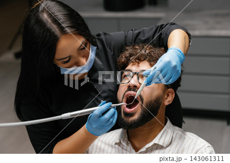 Dentist checking patient's teeth during oral examination Dentist checking patient's teeth during oral examination 143061311