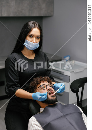 Dentist checking patient teeth during oral examination 143061312