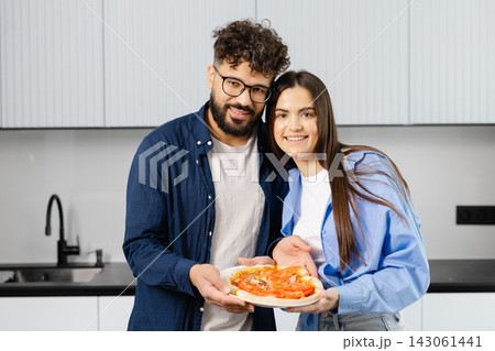 Happy couple preparing fresh homemade pizza in kitchen 143061441
