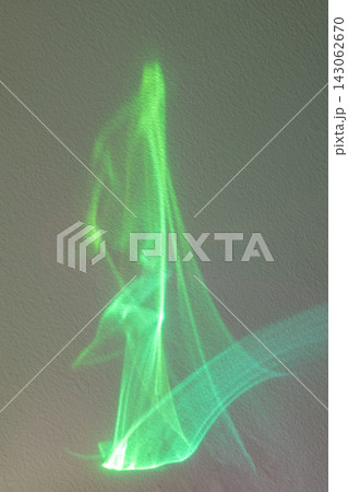 Green light projection forming an abstract glowing fabric-like shape on a textured wall Green light projection forming an abstract glowing fabric-like shape on a textured wall 143062670