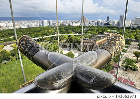 Traditional golden decorative architectural ornaments on the roof of Osaka Castle overlooking the city skyline. 143062971