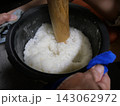 炊飯器の内釜で木製すりこぎを使いおはぎ用ご飯をつぶす 143062972