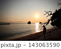 夕暮れの砂浜とたたずむ人物のシルエット 海に輝く夕日 143063590