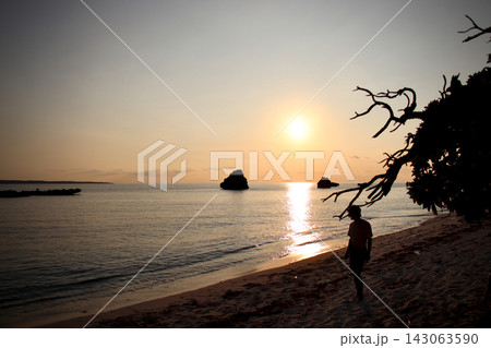 夕暮れの砂浜とたたずむ人物のシルエット 海に輝く夕日 夕暮れの砂浜とたたずむ人物のシルエット 海に輝く夕日 143063590