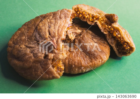 Dried figs with one cut open revealing the seeds and texture, showcasing healthy eating, natural snack options, and Mediterranean dessert ingredients on a green background Dried figs with one cut open revealing the seeds and texture, showcasing healthy eating, natural snack options, and Mediterranean dessert ingredients on a green background 143063690