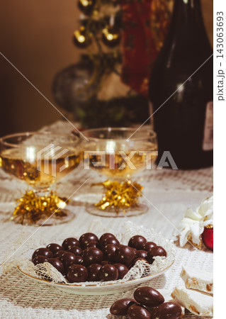 Festive table presenting two glasses of sparkling champagne alongside traditional nougat bars and rich chocolate almonds, symbolizing celebration during the holiday season. Festive table presenting two glasses of sparkling champagne alongside traditional nougat bars and rich chocolate almonds, symbolizing celebration during the holiday season. 143063693