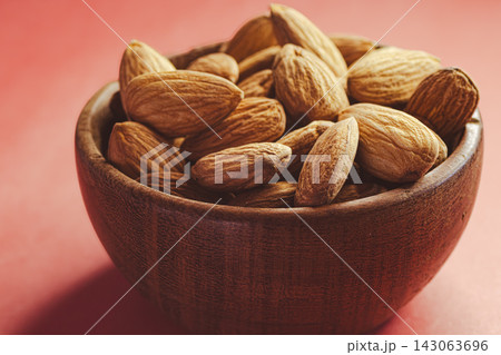 Almonds in a wooden bowl provide a crunchy snack, a healthy treat, or an appetizer, offering a delicious combination of energy and flavor. 143063696