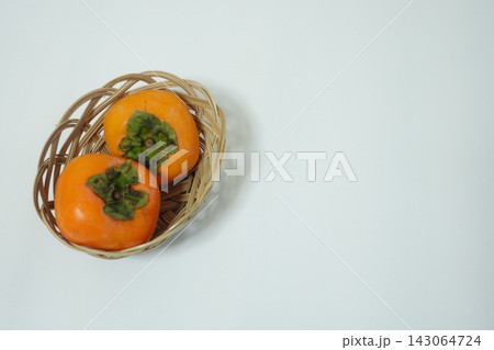 左側の籐かごに入れた二個の柿と広い右余白の写真として使える高解像度素材 左側の籐かごに入れた二個の柿と広い右余白の写真として使える高解像度素材 143064724