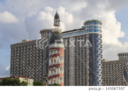 Batumi, Georgia - September 2, 2026: The architectural contrast of the historical style Chacha Tower dome standing in front of the modern Silk Road Sea Towers skyscrapers under a cloudy sky. Travel Batumi, Georgia - September 2, 2026: The architectural contrast of the historical style Chacha Tower dome standing in front of the modern Silk Road Sea Towers skyscrapers under a cloudy sky. Travel 143067397