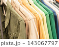 Colorful casual shirts hanging together on clothing rack in store 143067797