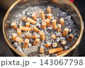 Glass ashtray filled with used cigarette butts and tobacco ashes 143067798