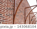 Red brick building with curved metal supports creating architectural perspective 143068104