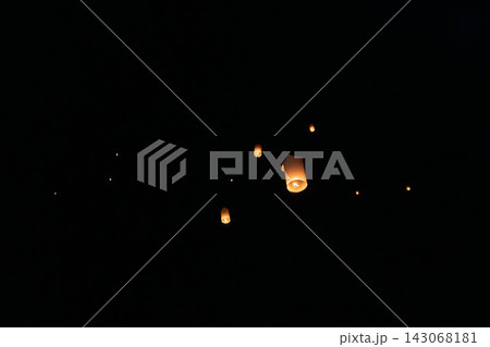 Glowing paper sky lanterns floating upward in night sky during festival celebration, warm amber light inside each lantern, scattered upward composition with serene hopeful atmosphere 143068181